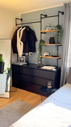 a bedroom with a bed, dresser and clothes rack in front of a mirror on the wall