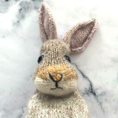 a knitted bunny rabbit sitting on top of snow covered ground with it's eyes open