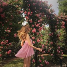 a woman in a pink dress standing next to flowers