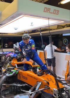 a man is working on an orange motorcycle