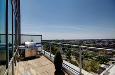 an outdoor grill on top of a building next to a large glass window with the city in the background