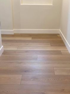 an empty room with white walls and wood flooring