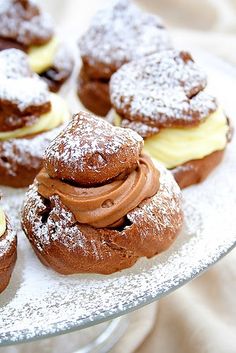 several pastries on a plate with powdered sugar and chocolate frosting in the middle