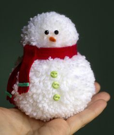 a hand holding a small white snowman with a red scarf around it's neck