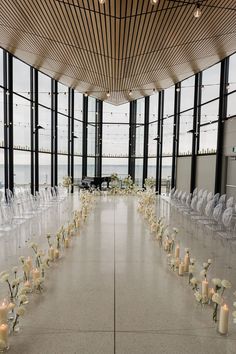 an indoor wedding setup with clear chairs and white flowers on the floor, along with candles