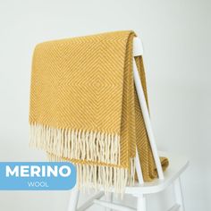 a yellow and white blanket sitting on top of a wooden chair next to a wall