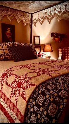 a bed with a red and white quilt on it's headboard in a bedroom