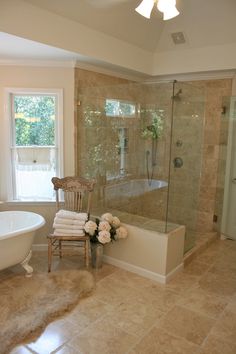 a bath room with a tub a chair and a window next to it's glass doors