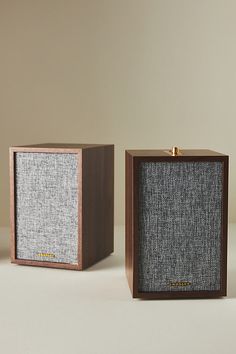 two speakers sitting side by side next to each other on top of a white surface