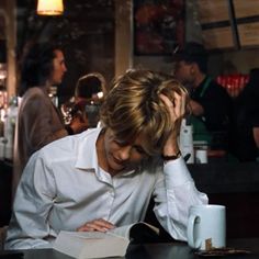 a person sitting at a table with a book in front of them and a cup