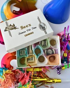 a box filled with candy and confetti next to streamers on the table