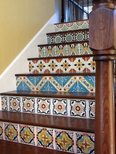 the stairs are decorated with colorful tiles and wooden handrails, along with a wood banister