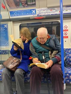 two people sitting on a train reading books