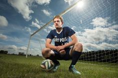 a man sitting on the ground next to a soccer ball in front of a goal