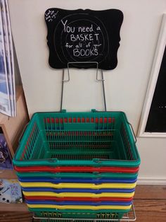 a stack of colorful plastic baskets sitting on top of a wooden floor next to a chalkboard