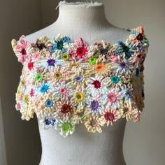 a white mannequin with multicolored crocheted flowers on it's chest