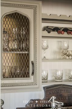 an old fashioned china cabinet with wine glasses on the top and bottom shelf in front of it