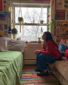 a woman sitting on a couch in front of a window with lots of decorations hanging from the windowsill