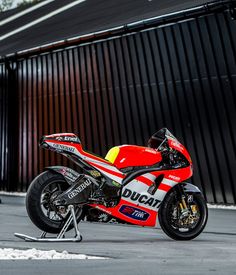 a red and white motorcycle parked next to a building