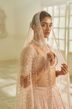 This lehenga set features tonal embroidery in delicate sequin and crystal. The blouse has a plunging neckline with crystal pieces at the center. The elbow sleeves has exaggerated tassels. The four sided embroidered dupatta has an all over jaal as well. The outfit has pink crystal drops.From Seema Gujral's Inara collection. DELIVERY TIMEPlease allow 8-12 weeks for your outfit to arrive. FABRIC DETAILSLehenga - organza, Bluose- Net, Dupatta - net Professional cleaning only. Glamorous Embellished Lehenga For Eid, Festive Glamorous Hand Embellished Dupatta, Glamorous Designer Lehenga For Eid, Glamorous Sequined Choli For Eid, Glamorous Semi-stitched Hand Embellished Dupatta, Glamorous Anarkali Set With Sheer Dupatta, Glamorous Traditional Drape Sets With Dupatta, Glamorous Embellished Choli For Eid, Glamorous Choli With Dupatta For Eid