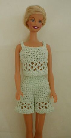 the doll is wearing a white crocheted dress and shorts with holes on it