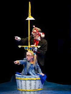 two children are sitting in a basket on stage