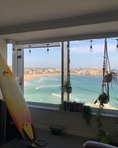 a surfboard leaning against a window overlooking the ocean