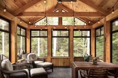 a room filled with lots of windows and furniture next to a wooden ceiling covered in lights