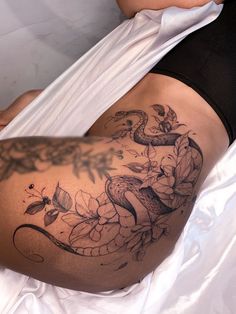 a woman laying on top of a bed next to a white sheet covered in tattoos