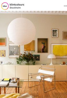 a living room filled with furniture and pictures on the wall next to a lamp shade