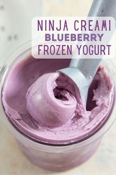 a frozen yogurt is in a glass with a spoon and the words, ninja cream blueberry frozen yogurt