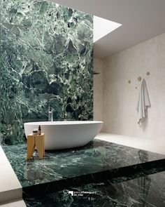 a bath tub sitting next to a white sink in a room with green marble walls