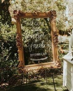 a sign that is sitting in the grass next to a chair and table with flowers on it