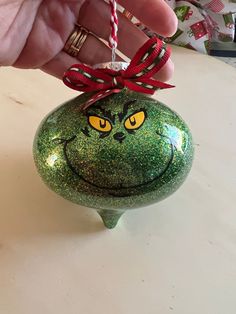 a hand holding a green ornament with a smiley face drawn on it's side