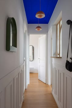 an empty hallway with white walls and wooden flooring is lit by blue ceiling lights