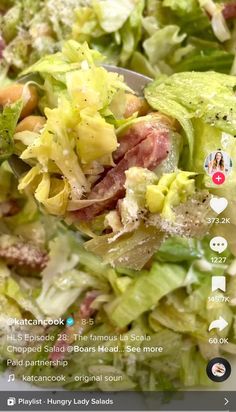 a salad with lettuce, meat and cheese on it is being held up by a spoon