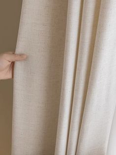 a person's hand is pulling up the curtain with their thumb, and they are holding on to it