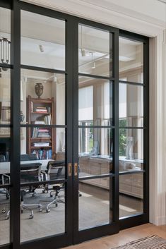 an office with glass doors leading to the living room