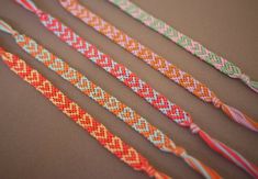 four different colored braided bracelets sitting on top of a table