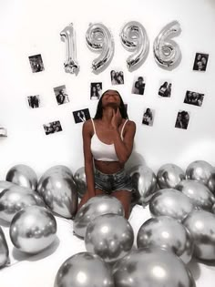 a woman sitting on the floor surrounded by balloons and photos with numbers in the background