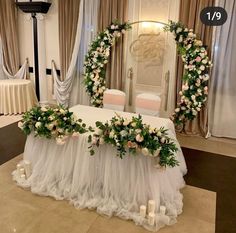 the table is decorated with white flowers and greenery for an elegant wedding or reception