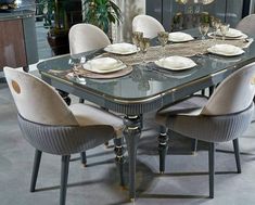 a dining room table set with white plates and silverware on it, surrounded by beige chairs