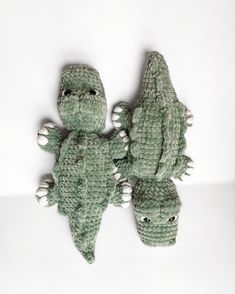 three green crocheted alligators sitting next to each other on a white surface