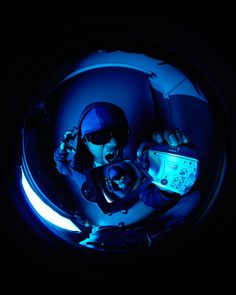 a man holding a camera in the dark with blue light coming from behind his head