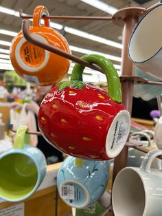 ceramic cups are hanging from the ceiling in a store with other items on display behind them