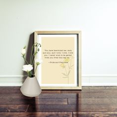 there is a vase with flowers in it on the floor next to a framed quote