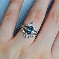 a woman's hand with a blue and white diamond ring on top of it