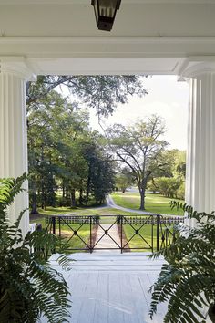 an open porch with columns and plants on either side