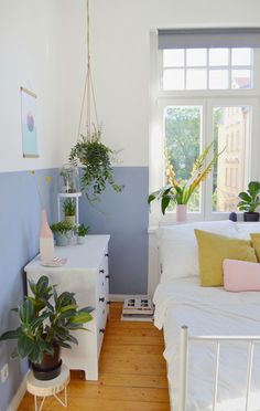 a bed room with a neatly made bed and some plants