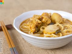 a white bowl filled with food next to chopsticks